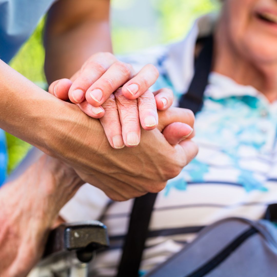 Senior and nurse holding hands