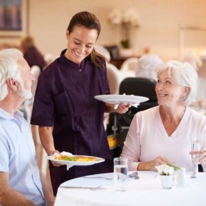 seniors being served dinner by staff