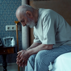 Elderly man sitting on the edge of his bed