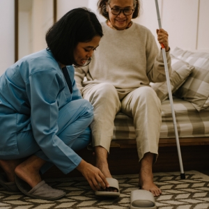 Woman helping a senior citizen put on her shoes