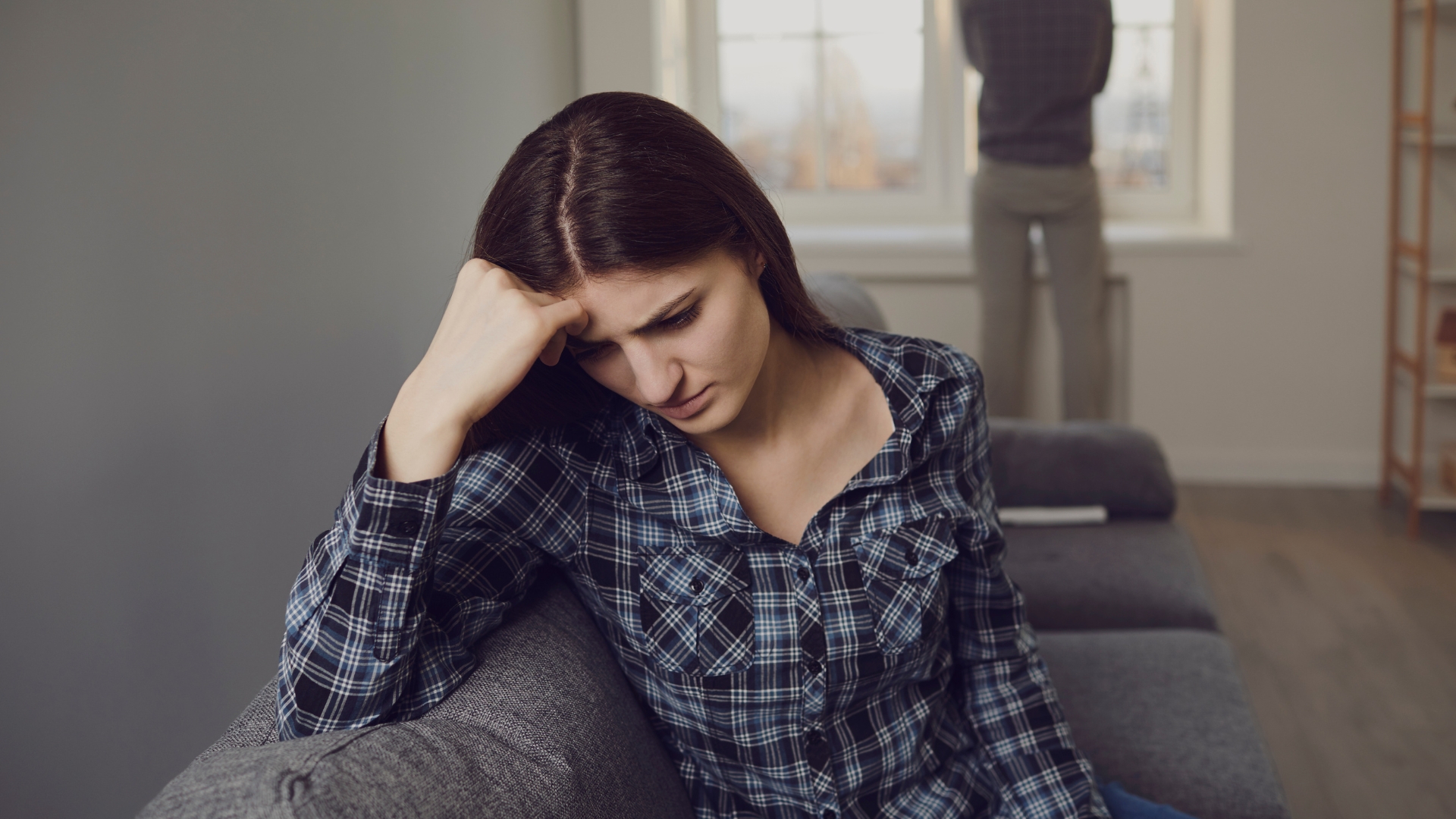 Woman with her head in her hands, and another person with their back turned to her