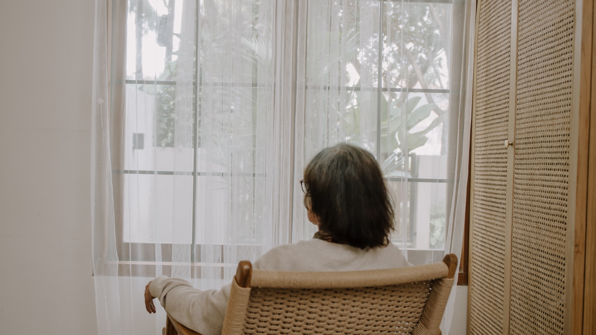 Elderly woman sitting and looking out her window