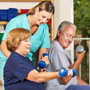 Two seniors and a caregiver during a physical therapy session.