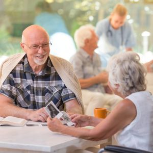 Two seniors looking in photos in a brightly lit communal area.