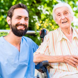 Senior and caregiver smiling together outdoors.
